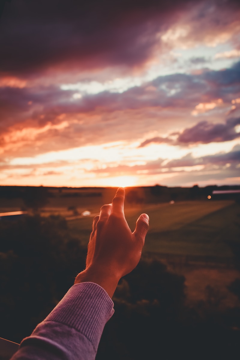 a person is holding their hand up to the sky